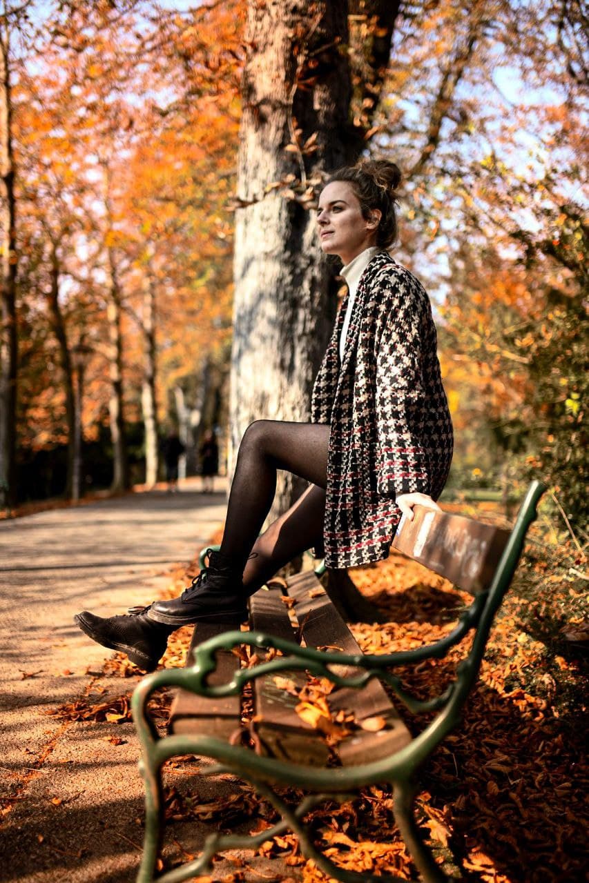 Dieses Bild zeigt die Gründerin Laura Schiller von Laura Schiller Texterstellung - Joy of Writiting. Sie sitzt auf einer Parkbank inmitten von Herbstlaub in einem Park.